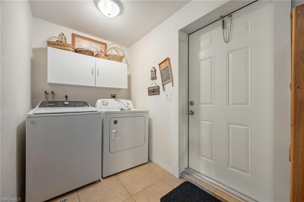 Laundry room with light tile patterned floors, separate washer and dryer, and cabinet space
