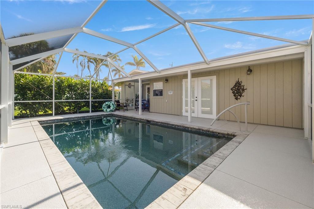 Swimming pool with glass enclosure, a patio, a sunroom, and french doors