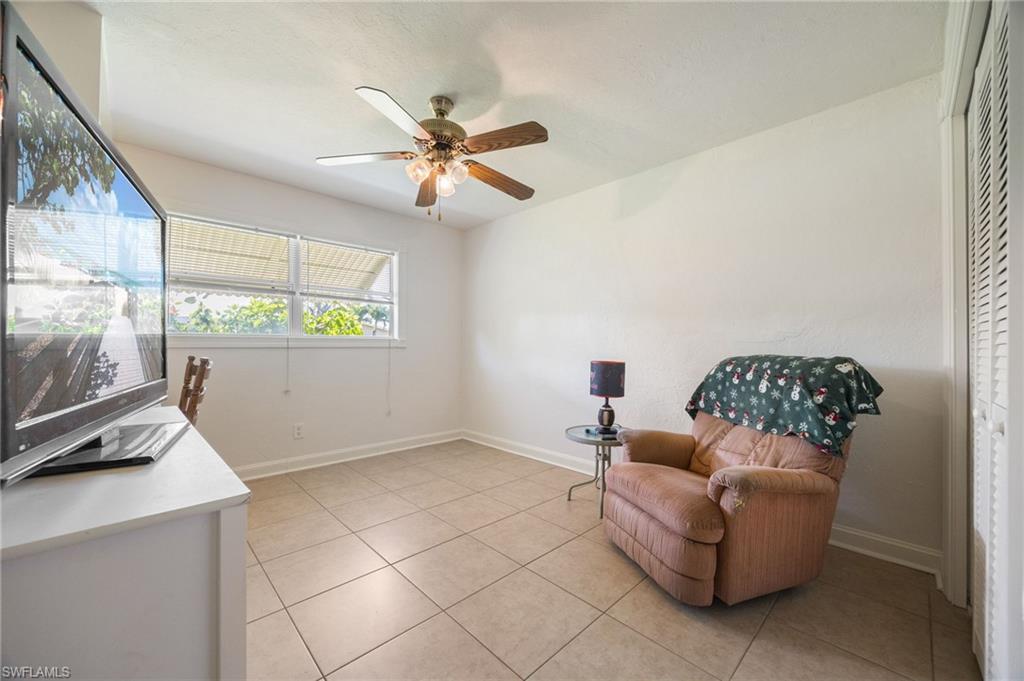 Living area featuring light tile patterned floors and a ceiling fan