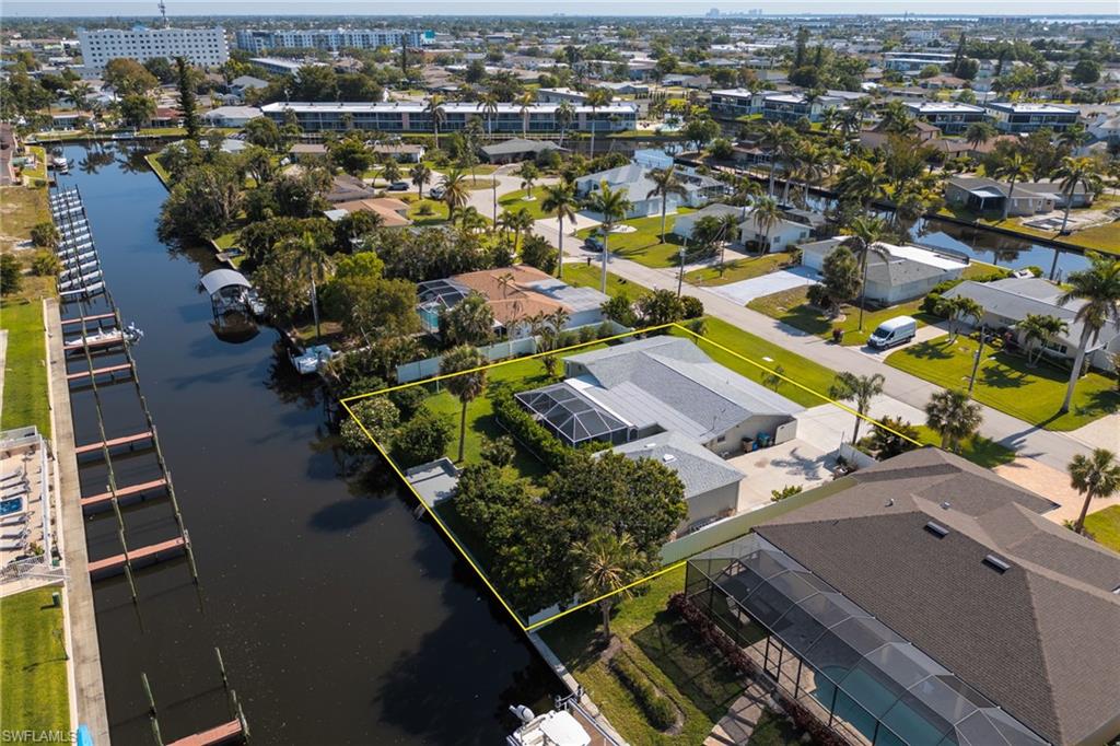 Aerial view of residential area with a nearby body of water and property parcel outlined