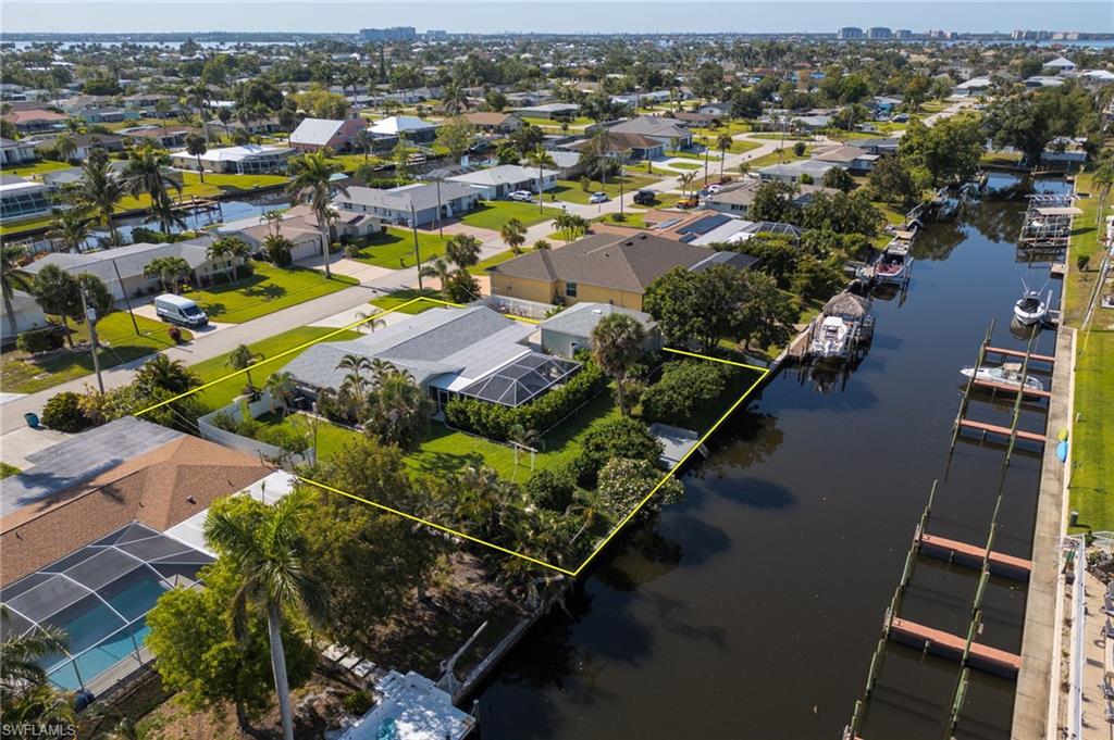 Aerial view of residential area with a large body of water and property parcel outlined