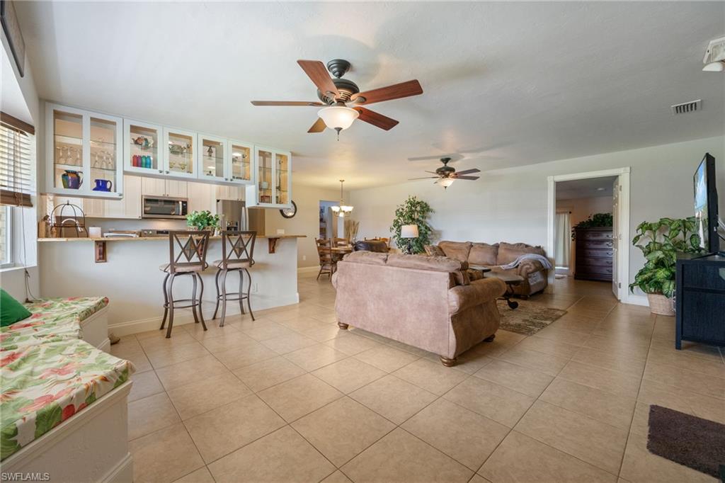 Living room with ceiling fan, light tile patterned floors, and a chandelier