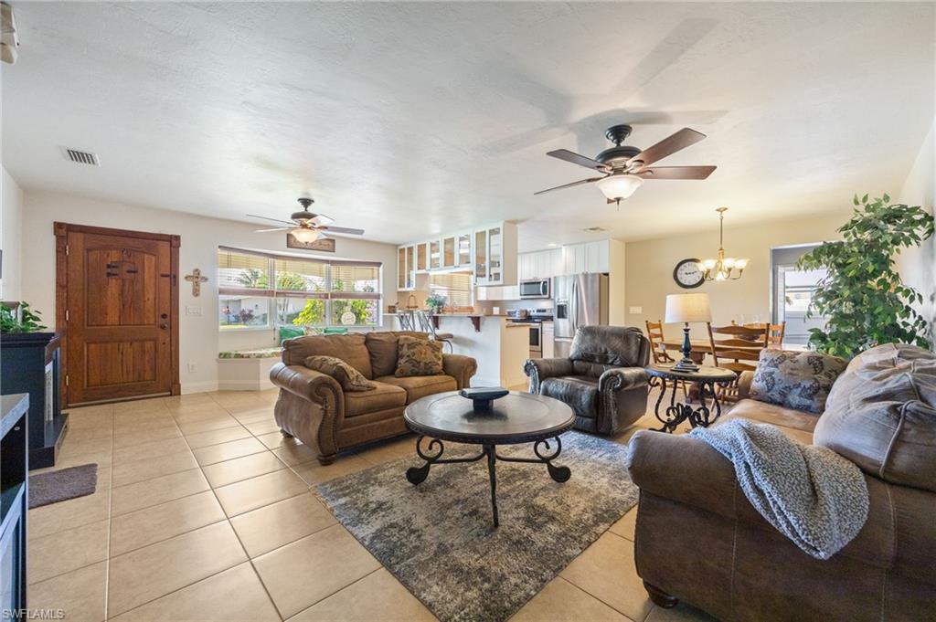 Living area with light tile patterned flooring, a ceiling fan, and healthy amount of natural light