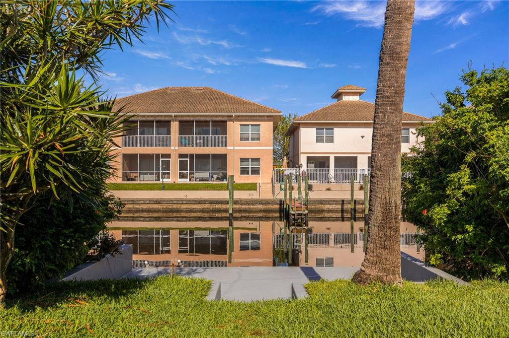 Rear view of house featuring a water view, a lawn, and stucco siding