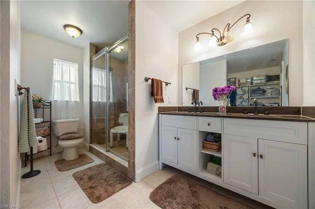 Bathroom with light tile patterned floors, a shower stall, and double vanity
