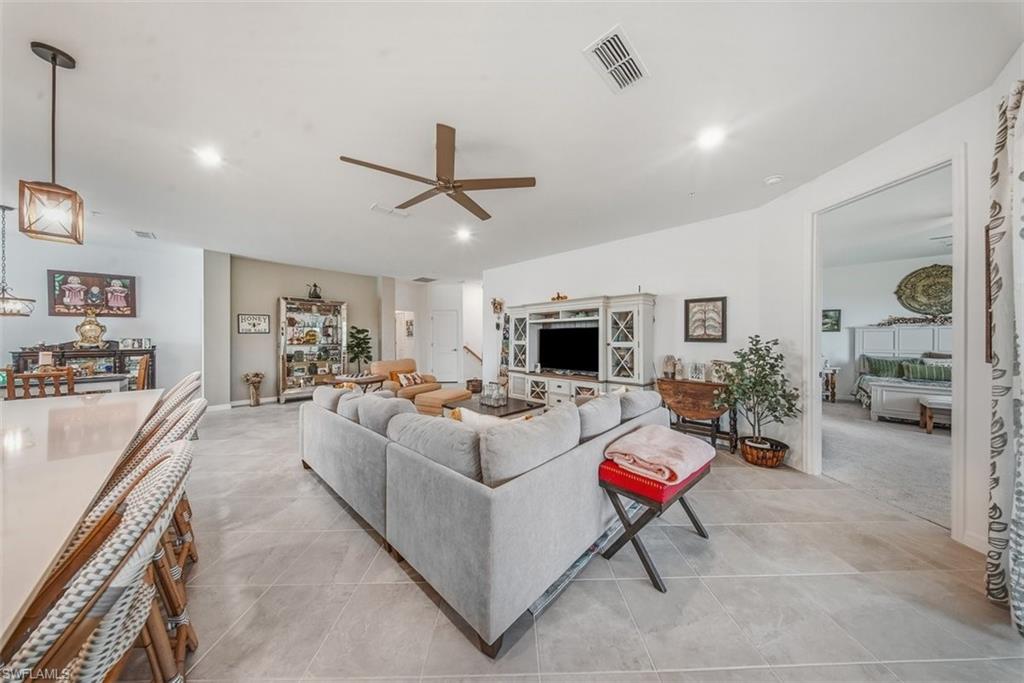 Living room with ceiling fan, light tile patterned flooring, and recessed lighting