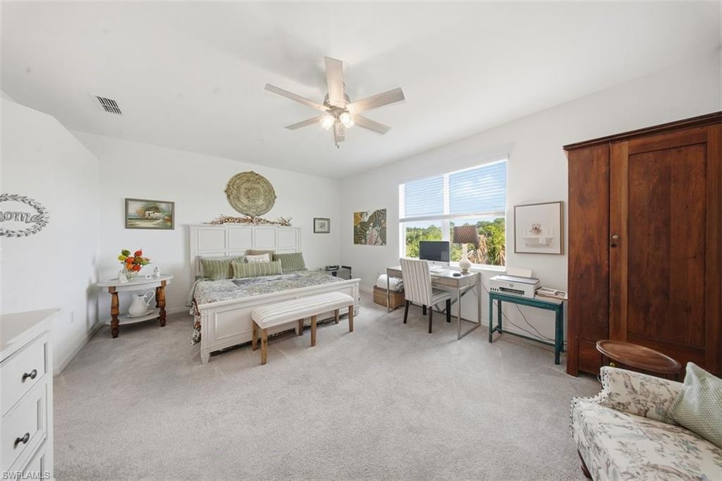 Bedroom featuring light colored carpet, a ceiling fan, and an office area