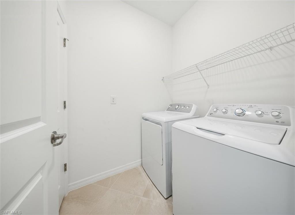 Laundry room with light tile patterned floors and washing machine and clothes dryer