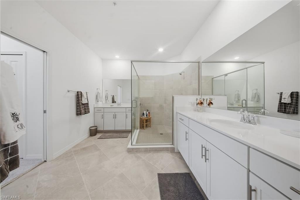 Bathroom featuring two vanities, a shower stall, recessed lighting, and light tile patterned floors