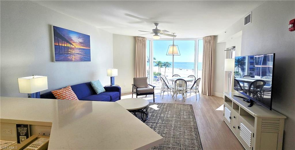 Living room featuring floor to ceiling windows, wood finished floors, and a ceiling fan