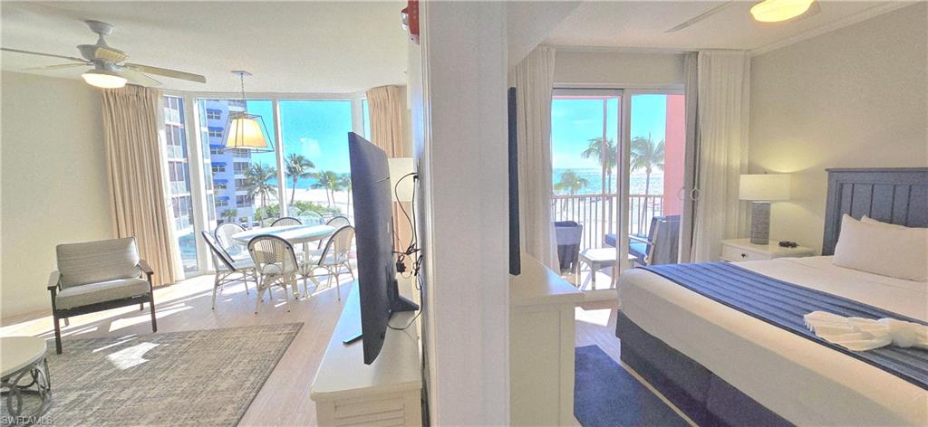Bedroom featuring ceiling fan, multiple windows, wood finished floors, floor to ceiling windows, and access to outside