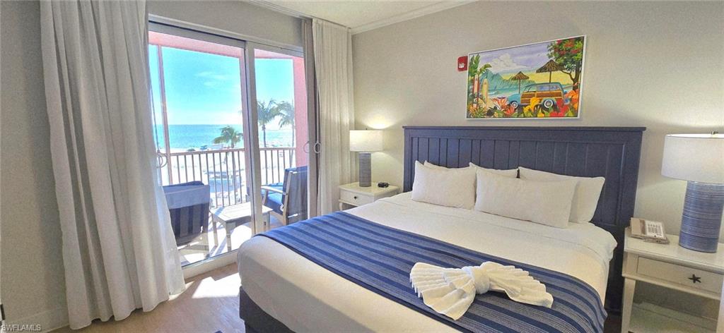 Bedroom featuring access to outside, a water view, wood finished floors, and ornamental molding