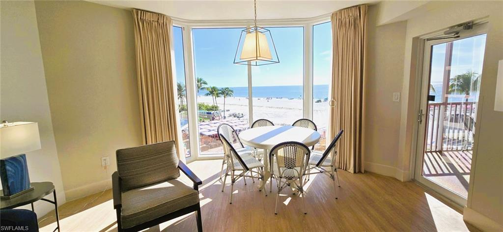 Dining area featuring expansive windows, light wood-style flooring, and view of water and beach
