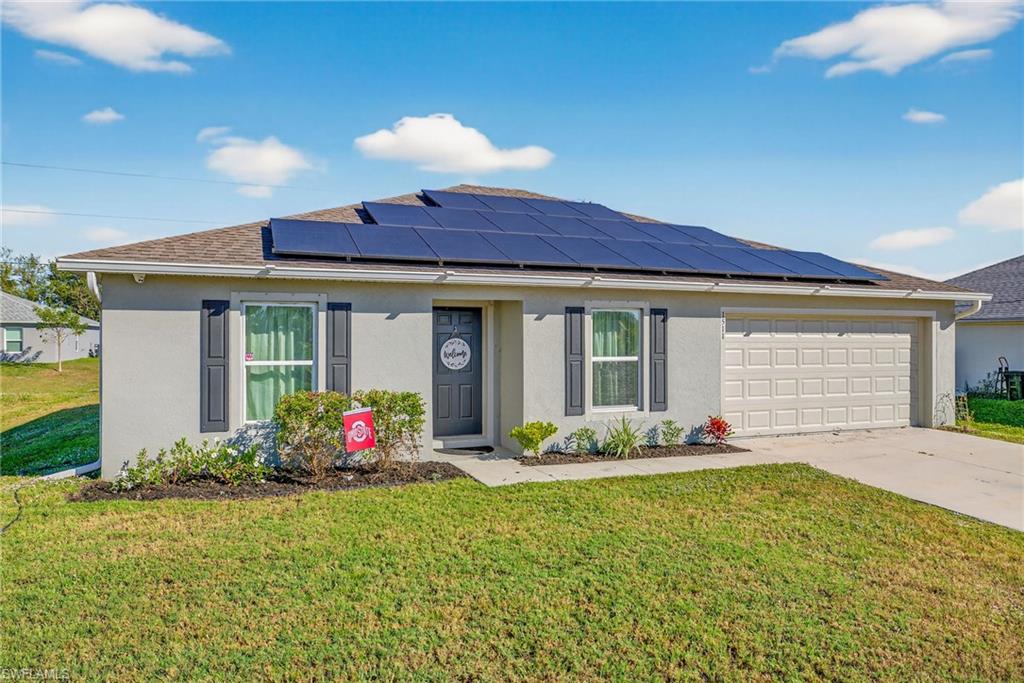 Single story home featuring stucco siding, a front yard, driveway, and solar panels