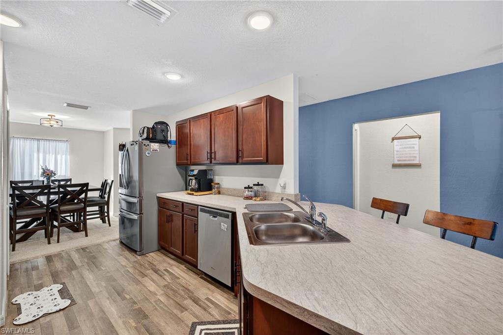 Kitchen with light countertops, light wood-type flooring, appliances with stainless steel finishes, a peninsula, and a breakfast bar area