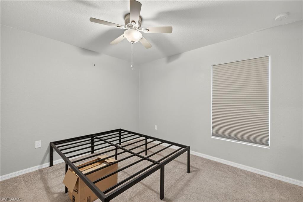 Bedroom with light carpet, ceiling fan, and a textured ceiling
