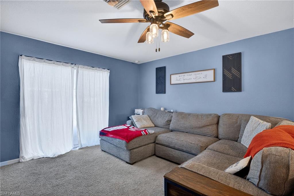 Living room featuring carpet flooring and a ceiling fan