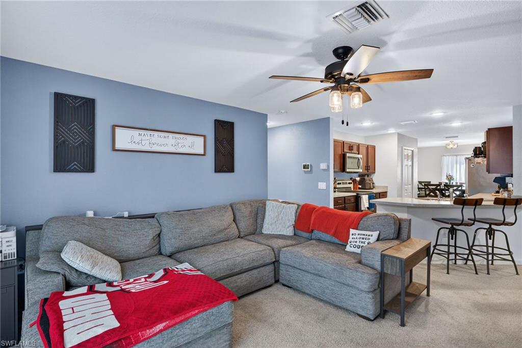 Living area with light colored carpet and ceiling fan