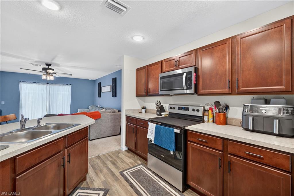 Kitchen featuring stainless steel appliances, light countertops, light wood-style flooring, ceiling fan, and open floor plan