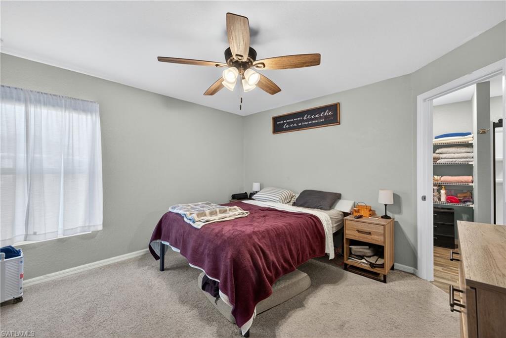 Bedroom with a spacious closet, ceiling fan, and light colored carpet