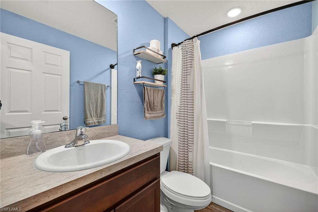 Full bathroom featuring shower / tub combo, vanity, and a textured wall