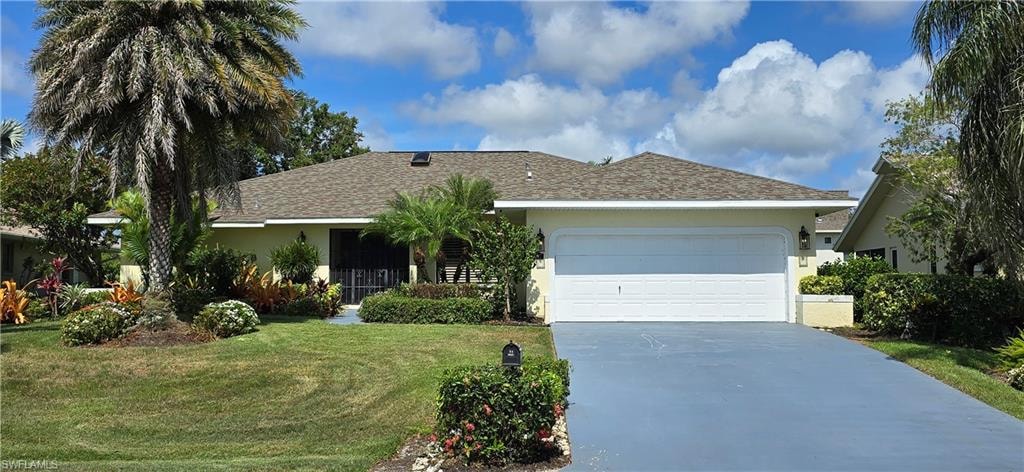 Ranch-style house with stucco siding, a front yard, driveway, a garage, and roof with shingles
