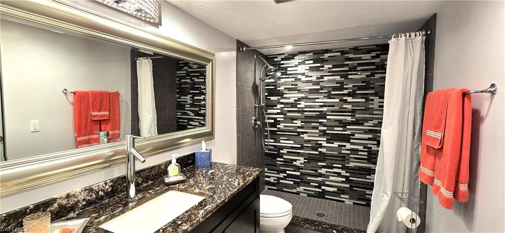 Bathroom with vanity, a shower with shower curtain, and toilet