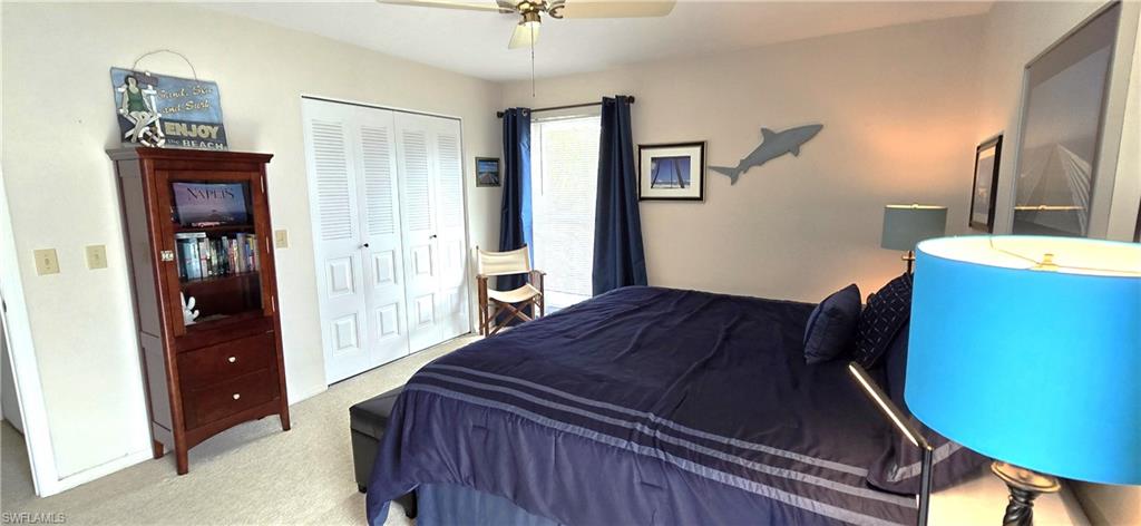 Carpeted bedroom featuring ceiling fan and a closet