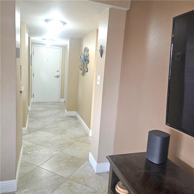 Corridor with baseboards and light tile patterned floors
