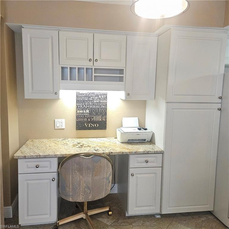 Office with built in desk and dark tile patterned floors