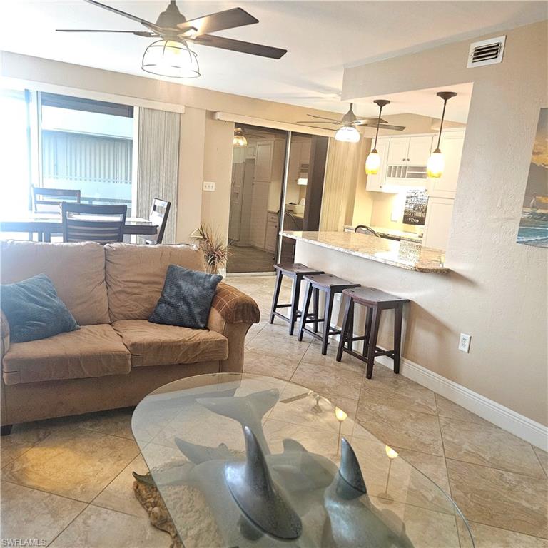Living area featuring ceiling fan and light tile patterned floors