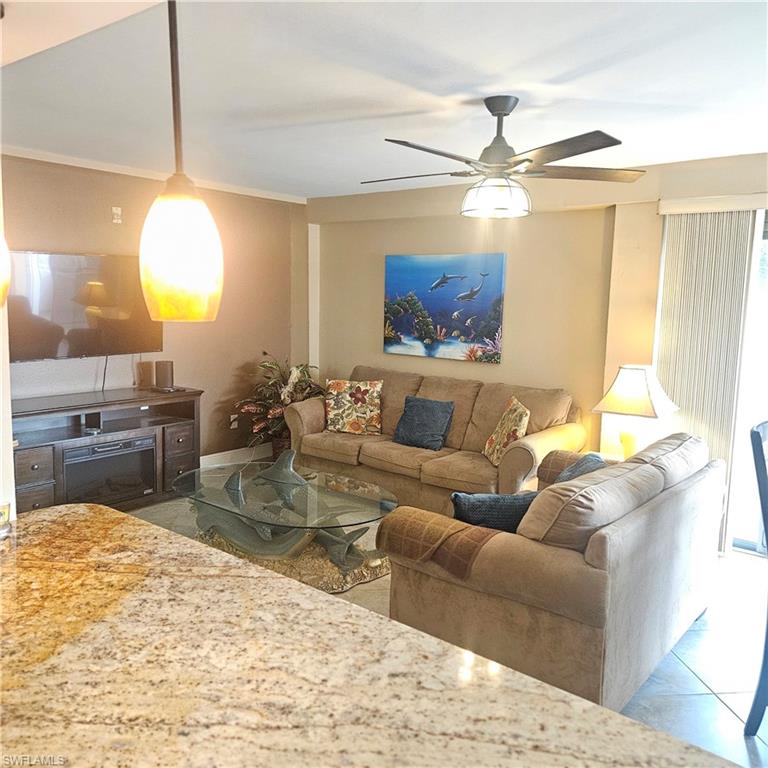 Tiled living area featuring a ceiling fan and crown molding