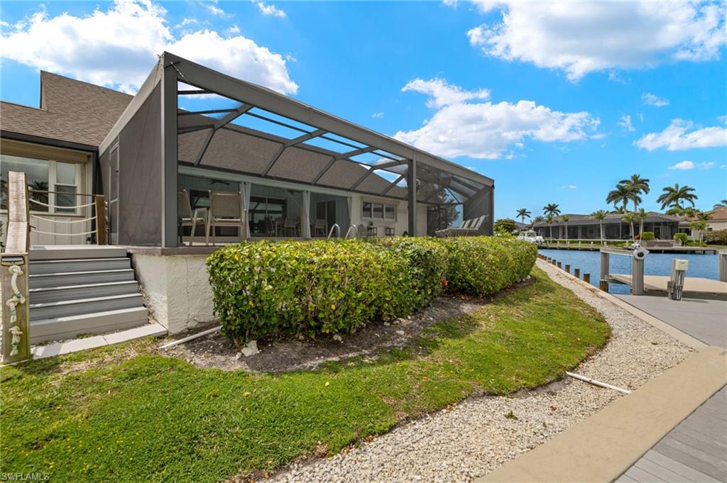 Back of property featuring a lanai, a sunroom, and a water view
