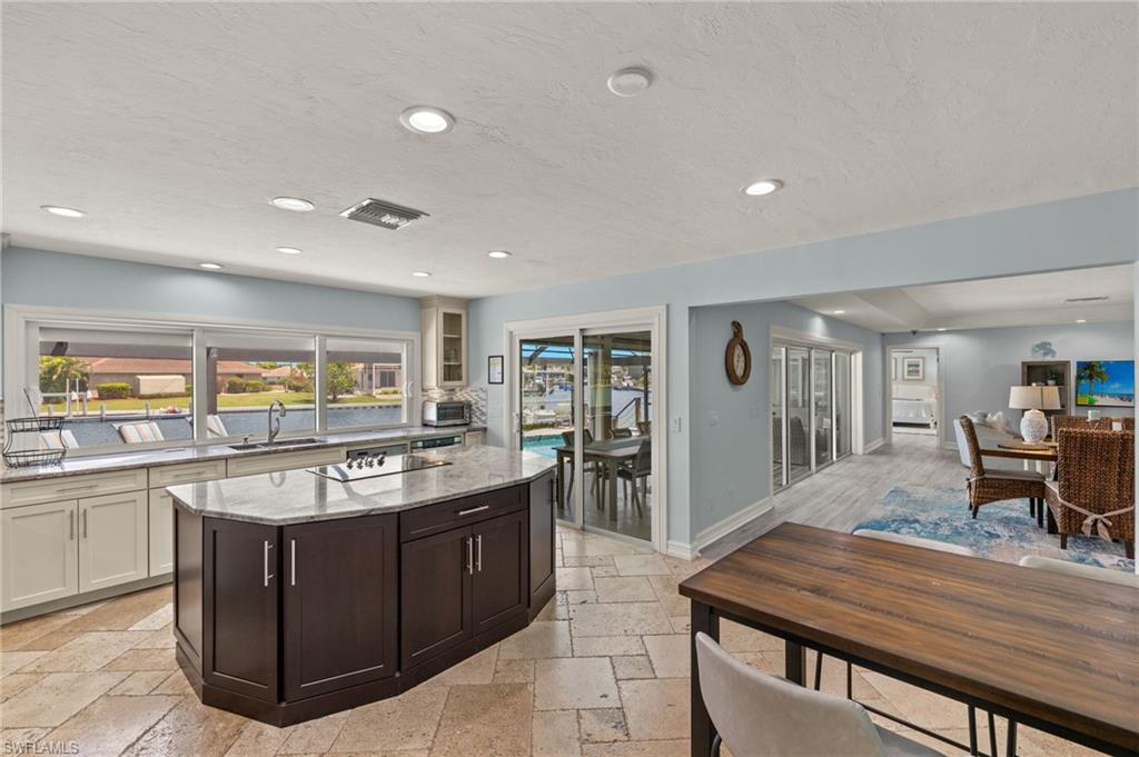 Kitchen featuring light stone countertops, recessed lighting, dark brown cabinets, a textured ceiling, and stone tile floors