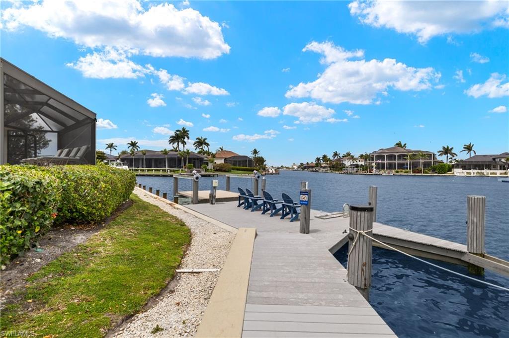 Dock area with a water view, a sunroom, glass enclosure, and a residential view