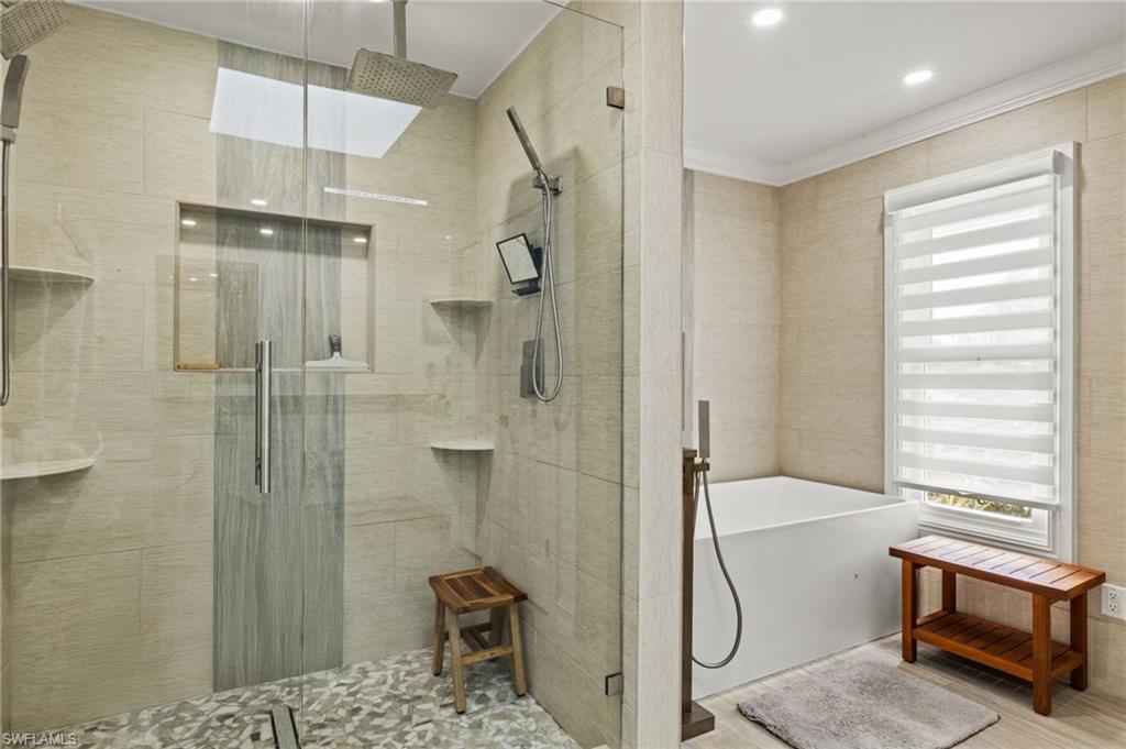 Bathroom featuring a freestanding tub, a stall shower, tile walls, and wood finished floors