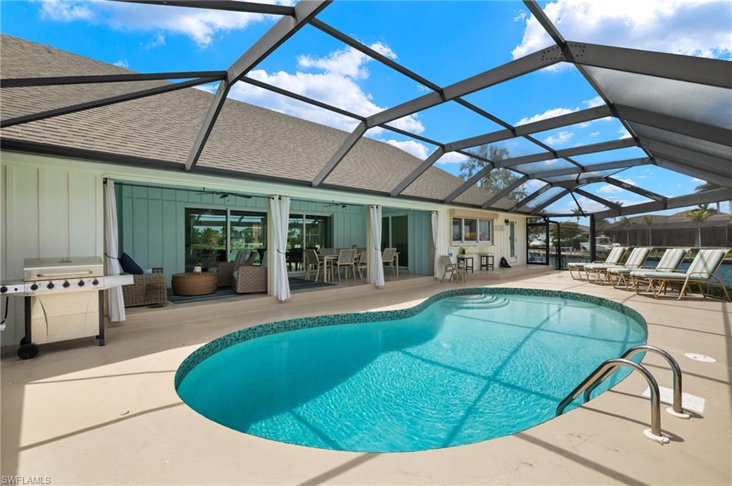 Outdoor pool with a sunroom, a patio area, a grill, a lanai, and outdoor dining space