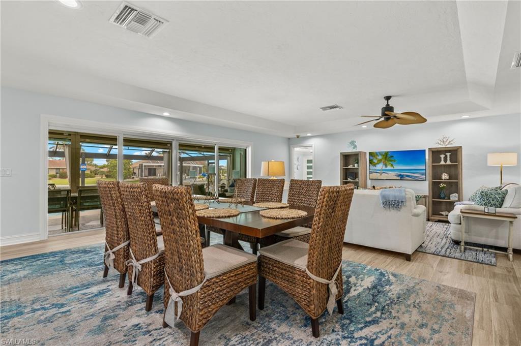 Dining area with recessed lighting, light wood-style floors, a ceiling fan, and a tray ceiling