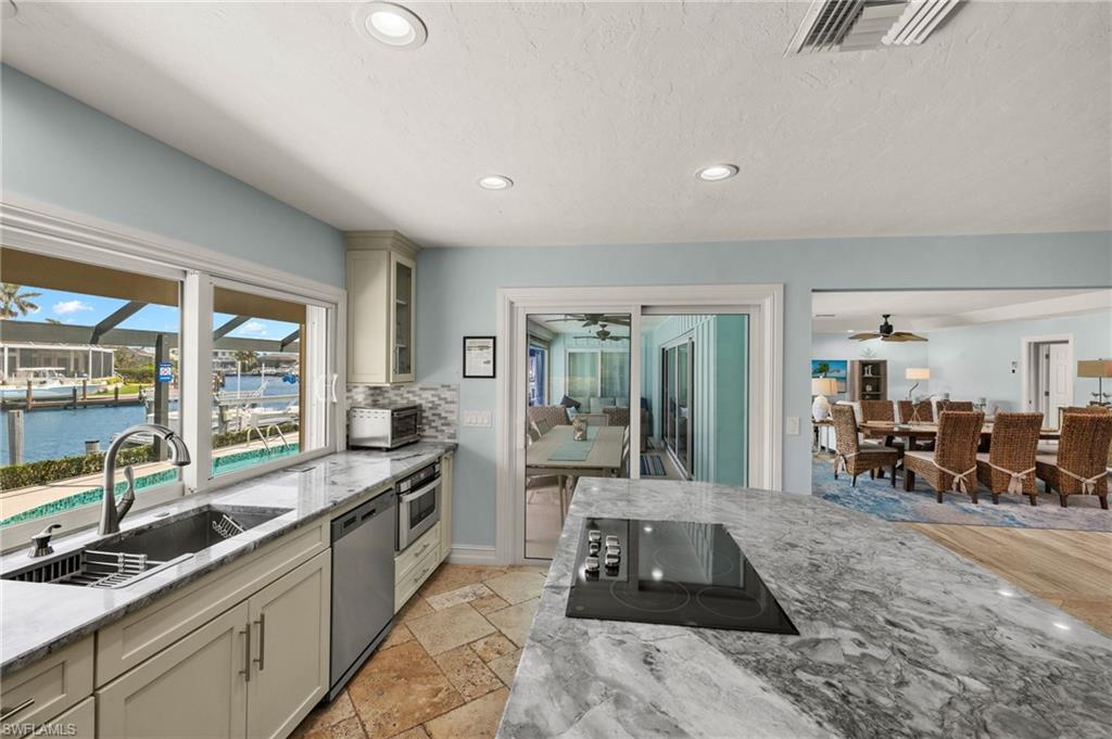 Kitchen featuring light stone counters, stainless steel appliances, recessed lighting, glass insert cabinets, and a water view