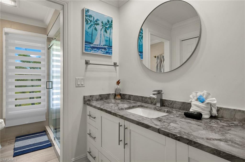 Full bathroom featuring vanity, crown molding, a stall shower, and light wood-style floors