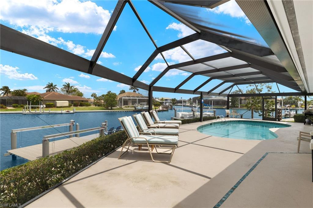 Swimming pool featuring a patio area, a dock, a water view, boat lift, and a sunroom