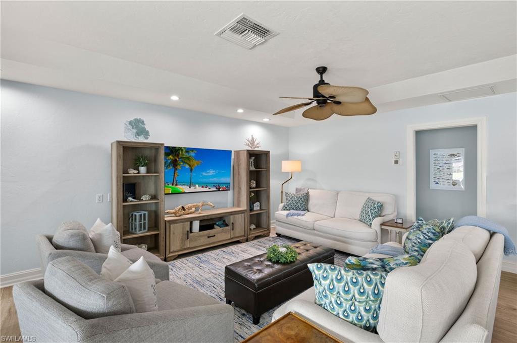 Living area with wood finished floors, a ceiling fan, and recessed lighting