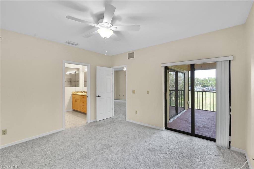 Unfurnished bedroom featuring access to outside, light carpet, ceiling fan, and ensuite bath