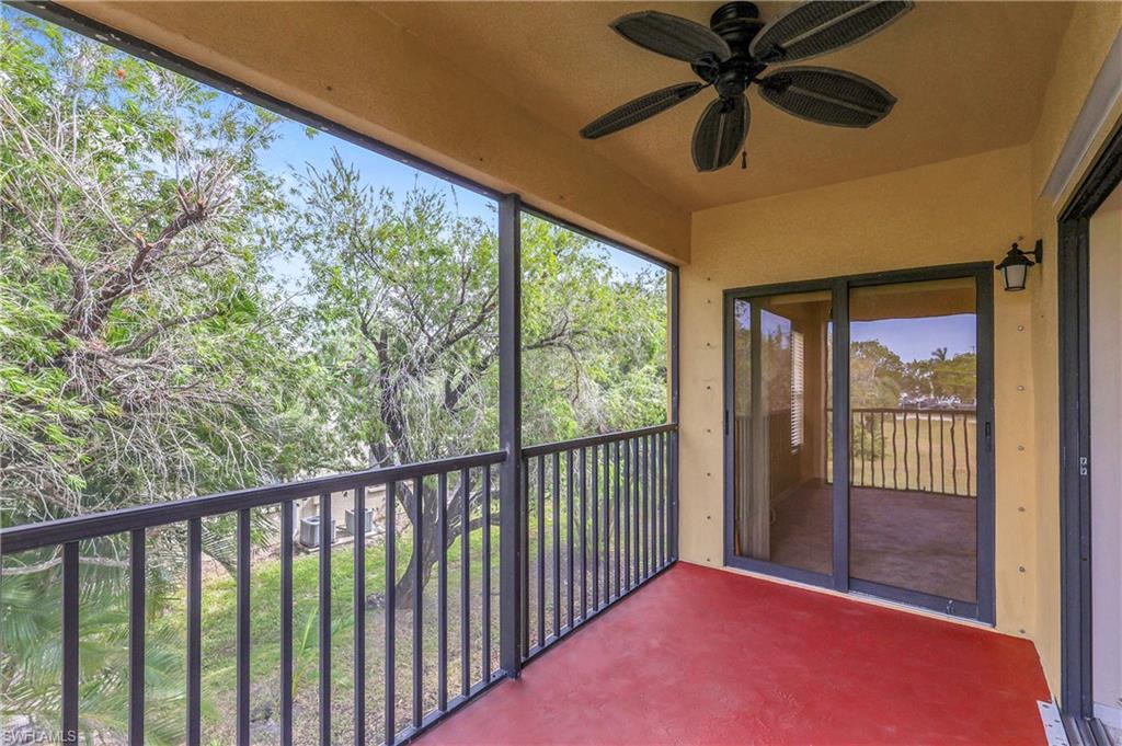 Balcony featuring a ceiling fan and view of wooded area