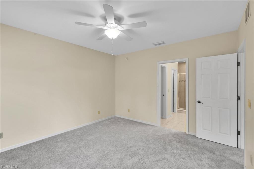 Unfurnished bedroom with light colored carpet, a ceiling fan, and connected bathroom