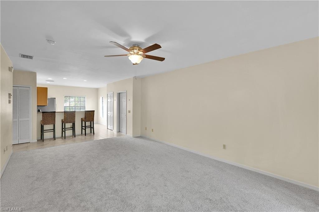 Unfurnished living room featuring light carpet and ceiling fan