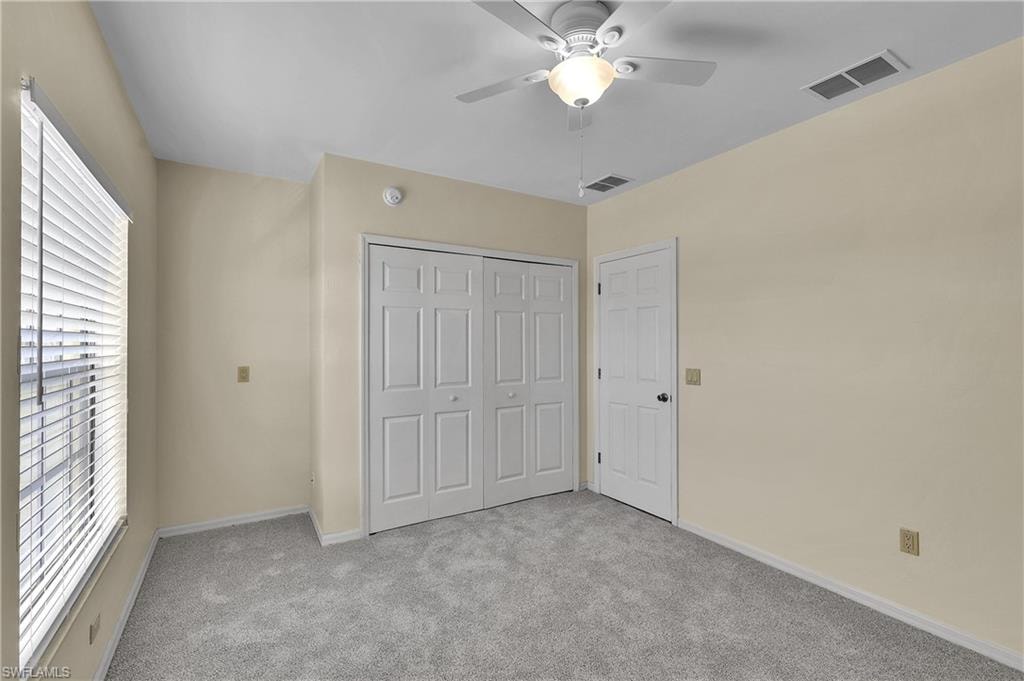 Unfurnished bedroom with light carpet, a closet, and a ceiling fan