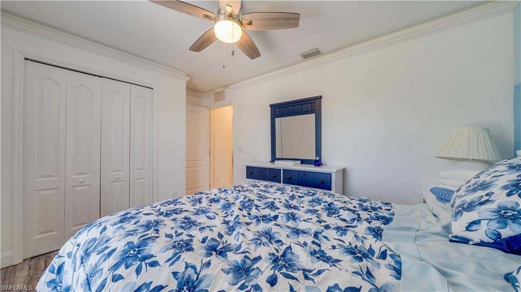 Bedroom with crown molding, a closet, ceiling fan, and wood finished floors
