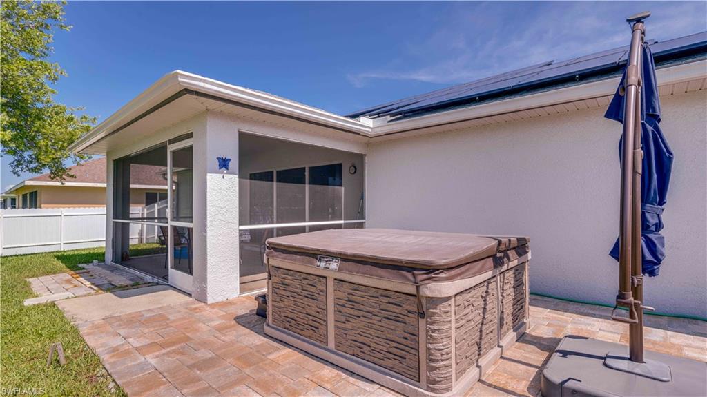 View of patio featuring a hot tub and a sunroom