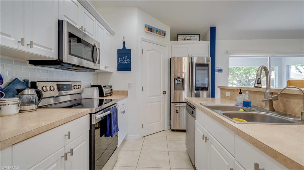 Kitchen with backsplash, stainless steel appliances, and white cabinetry